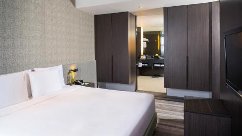 a bedroom with a large white bed and a bathroom at Holiday Inn Bangkok Sukhumvit by IHG in Bangkok