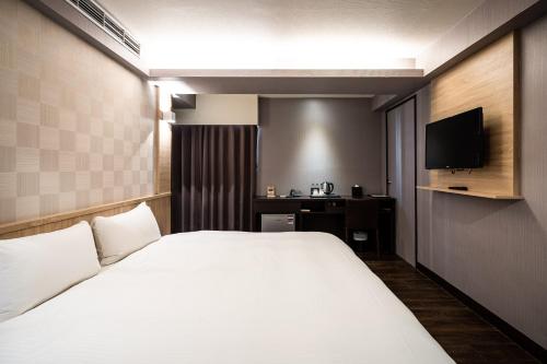 a hotel room with a large bed and a television at Global Traveler Hotel in Kaohsiung