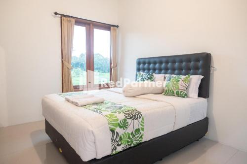 1 dormitorio con 1 cama grande y ventana en Twin House near UII Yogyakarta Mitra RedDoorz, en Yogyakarta