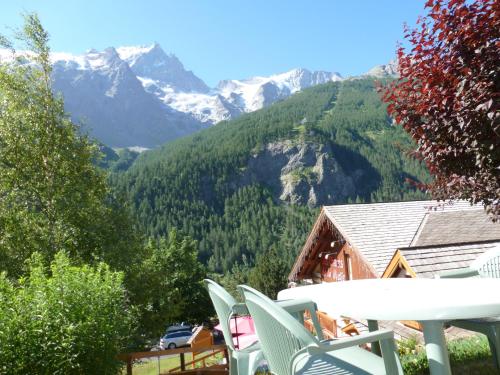 a table and chairs on a balcony with mountains at Panoramic Village - Locations vue Glaciers - Chez Philippe in La Grave