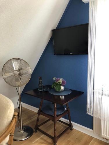 a room with a table with a fan and a blue wall at Loft Johanns Hochsitz in Beverungen
