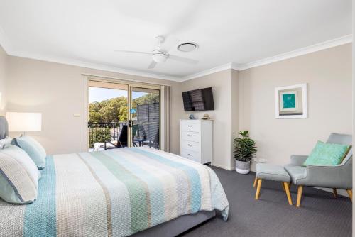 a bedroom with a bed and a chair and a window at Aqua Lagoon - Great Family Beach Getaway in Nelson Bay