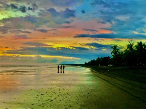 two people walking on the beach at sunset at Beachfront Paradise in Manuel Antonio