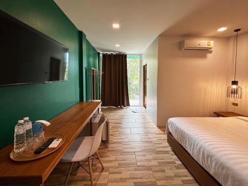 a hotel room with a bed and a desk and a bed and a room at Plernpetch Hotel in Surat Thani