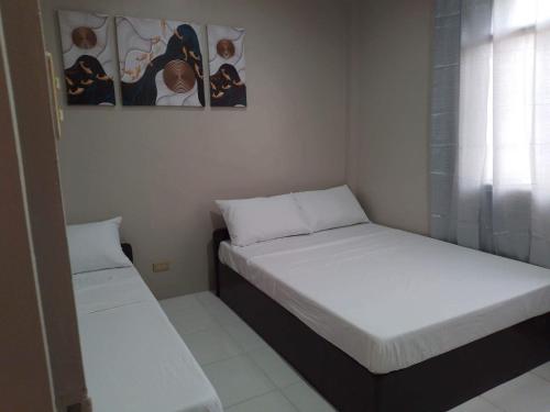 two beds in a small room with white sheets at Tresha Lance Apartelle in Boracay