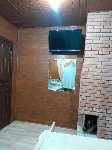 a room with a brick fireplace with a flat screen tv at Cabanas dos Pinheiros in São Francisco de Paula