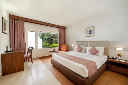 a hotel room with a bed and a desk and a window at Sterling Yercaud in Yercaud