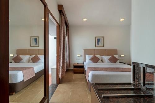 a hotel room with two beds and a mirror at Sterling Yercaud in Yercaud