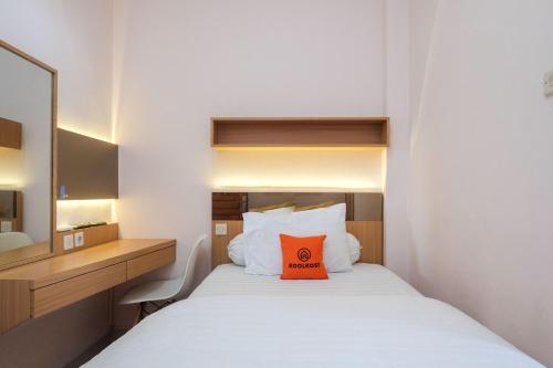 a bedroom with a bed with a orange pillow on it at KoolKost Syariah near Taman Sriwedari Laweyan in Solo