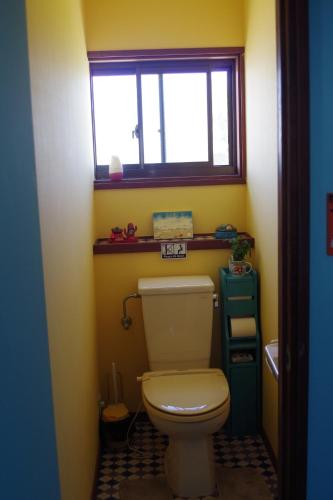 La salle de bains est pourvue de toilettes blanches et d'une fenêtre. dans l'établissement Finecamp Guesthouse Share Room 相部屋, à Miyazaki