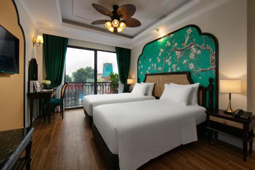 a bedroom with two beds and a green wall at La Passion Hanoi Hotel & Apartment in Hanoi