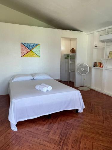 a bedroom with a white bed and a painting on the wall at Christina's Guest House OFFICIAL in Little Corn Island
