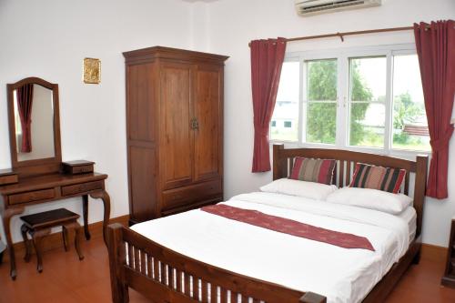a bedroom with a bed and a dresser and a mirror at P and A Thai Lanna Resort in Chiang Mai