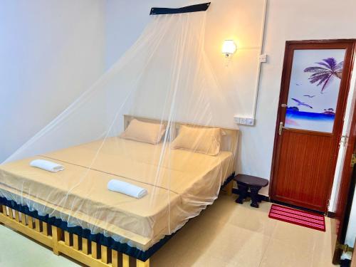 a bedroom with a bed with a mosquito net at Mangrove Bay Inn in Weligama