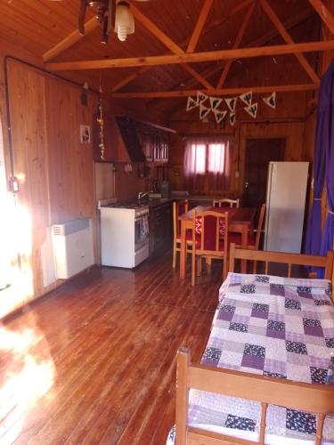 a kitchen and dining room of a cabin with wooden floors at Cabañas maiten in El Maitén