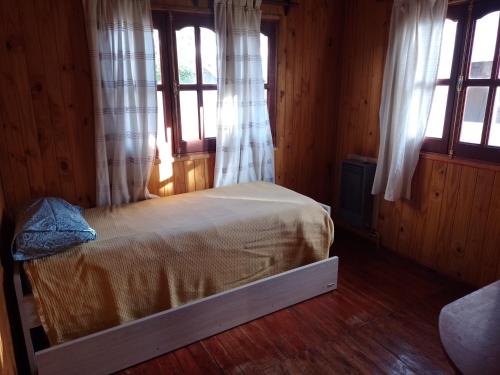 Un dormitorio con una cama en una habitación con ventanas. en Cabañas maiten, en El Maitén