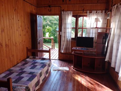 ein Schlafzimmer mit einem Bett und einem TV in einer Hütte in der Unterkunft Cabañas maiten in El Maitén