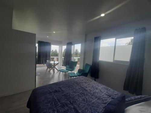 1 dormitorio con 1 cama y algunas sillas y ventanas en Mai'i Villa 2 - Muri, en Avarua