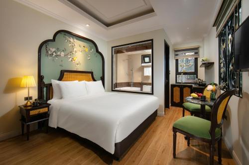 a bedroom with a large white bed and a chair at La Passion Hanoi Hotel & Apartment in Hanoi