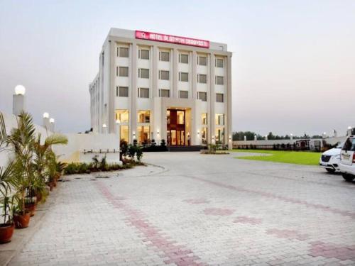 a large white building with a red sign on it at Hotel Platinum Shravasti in Katra