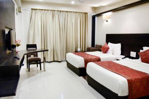 a hotel room with two beds and a desk at Hotel Platinum Shravasti in Katra
