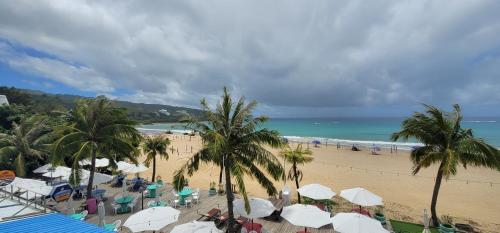 a beach with palm trees and white umbrellas and the ocean at A&L Inn 戀灣旅棧 in Nanwan