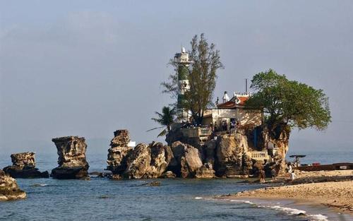 ein Haus auf einer felsigen Insel mit einem Leuchtturm in der Unterkunft Kim Huong Quang Hotel in Phu Quoc