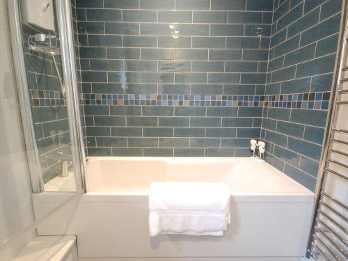 ein Badezimmer mit einer Badewanne mit blauen Fliesen in der Unterkunft Crabbe Corner in Aldeburgh