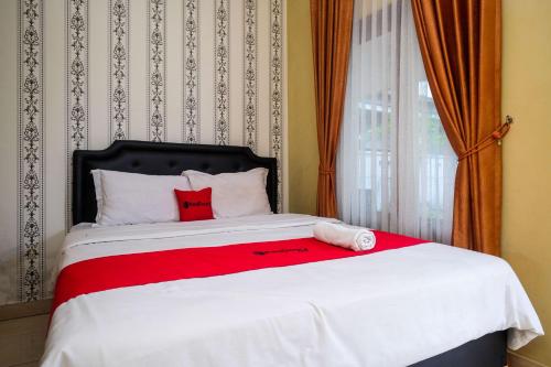 Una cama con dos almohadas rojas encima. en RedDoorz at Paris Ocean, en Yogyakarta