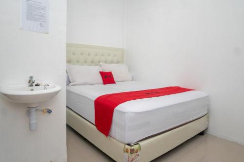 a white bedroom with a bed and a sink at RedDoorz Syariah near Pelabuhan Ulee Lheue Banda Aceh in Banda Aceh