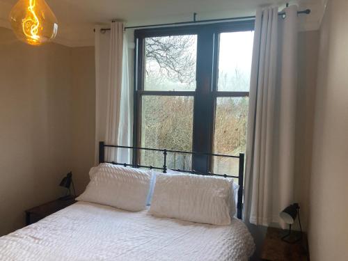 a bedroom with a bed and a large window at Uist Cottage in Kingussie