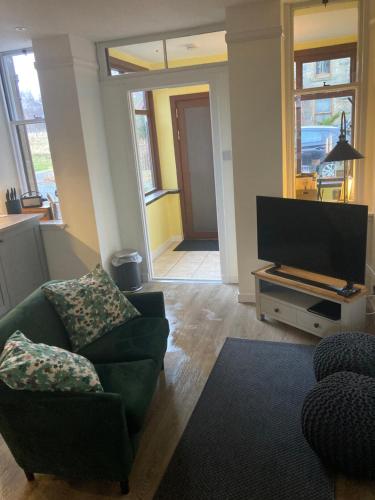 uma sala de estar com um sofá e uma televisão de ecrã plano em Uist Cottage em Kingussie
