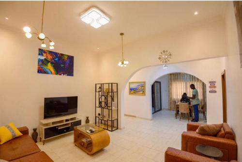 a living room with a couch and a tv at Bays Lodge - East Legon in Accra