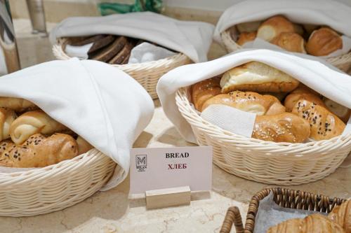 タシュケントにあるMilan Hotelのテーブルの上には、さまざまな種類のパンが入った3つのバスケットがある