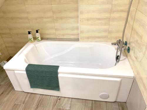 a white bath tub with a green towel in a bathroom at My Homestay in Longtan