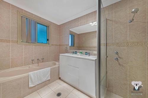 a bathroom with a tub and a sink and a shower at KozyGuru | Penrith | Cosy 4BED House | Free Internet in Penrith