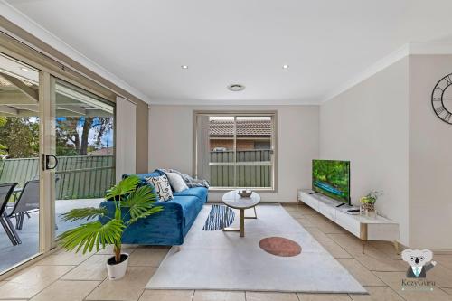 a living room with a blue couch and a tv at KozyGuru | Penrith | Cosy 4BED House | Free Internet in Penrith