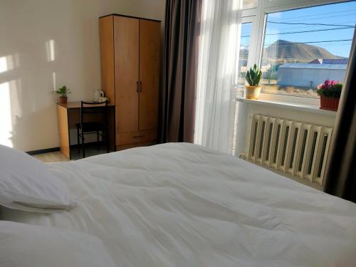 a bedroom with a white bed and a window at The Lake Townhouse in Cholpon-Ata