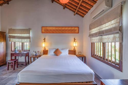 Schlafzimmer mit einem großen weißen Bett und Fenstern in der Unterkunft Gita Boutique Villa in Hoi An