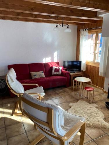 a living room with a red couch and chairs at Chalet Cocoon in Val dʼIlliez