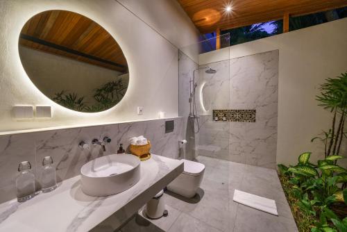 ein Badezimmer mit einem Waschbecken, einem WC und einem Spiegel in der Unterkunft Villa Satiya - Unique and stylish 4-bdr pool villa in Pererenan! in Canggu