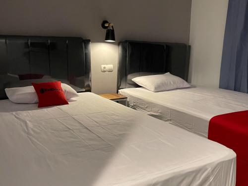 een kamer met 2 bedden met witte lakens en een rood kussen bij RedDoorz Plus near Alun Alun Kota Bora in Blora