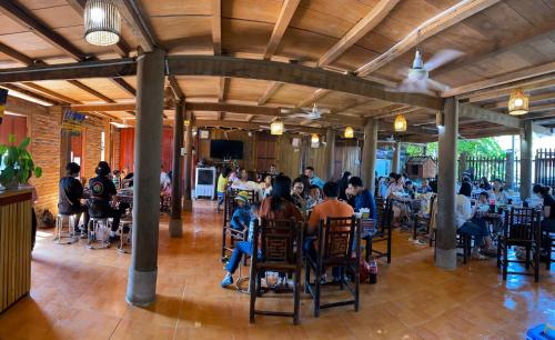 a group of people sitting at tables in a restaurant at Homestay Rung Xanh Huu Lien in Làng Ben