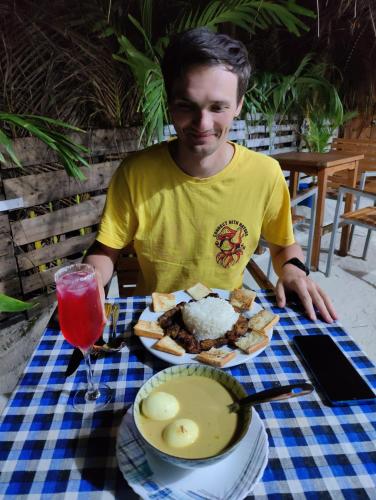a man sitting at a table with a plate of food at Rashuthere Maldives in Rasdu