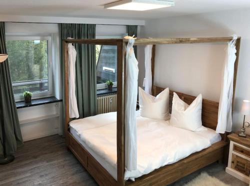 1 dormitorio con cama con dosel y almohadas blancas en Fewo Nartura: Modern – Idyllisch – stilvoll – ruhig, en Sankt Andreasberg