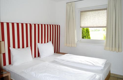 two beds in a room with a red and white striped wall at AvenidA Style Appartements by Alpin Rentals - incl Summercard in Kaprun