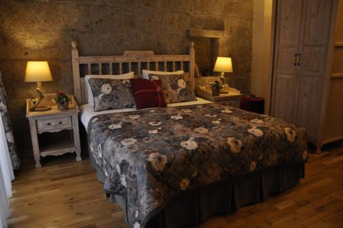 a bedroom with a large bed and two tables with lamps at Assos Sunaba Kasri Hotel in Behramkale
