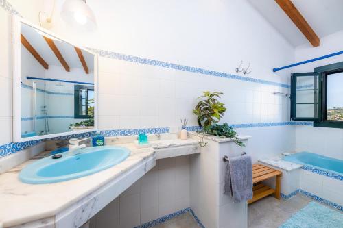 uma casa de banho azul e branca com um lavatório e uma banheira em El Olivo em Inca