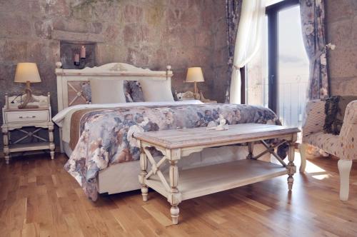 a bedroom with a bed and a table and a chair at Assos Sunaba Kasri Hotel in Behramkale