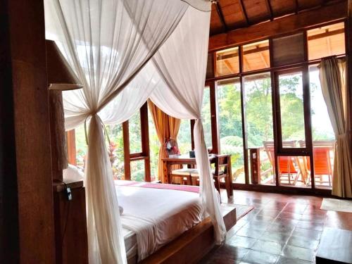 a bedroom with a canopy bed in a room with windows at Sang Tirta Resort in Penebel
